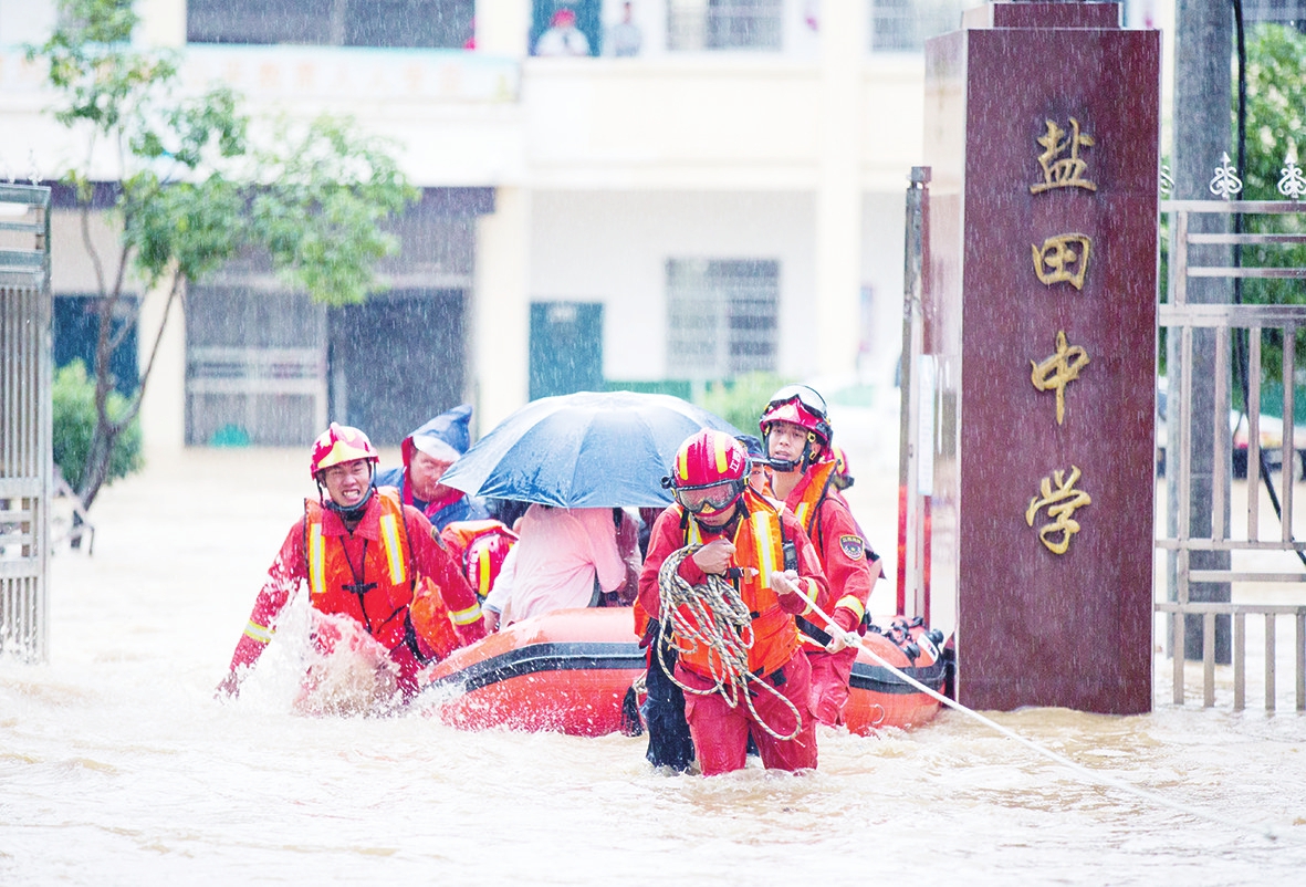 7月8日,在江西省九江市都昌县大港镇盐田中学,救援人员冒雨将学生们